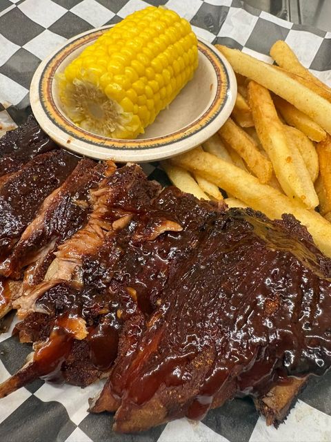 Rack of glazed barbecue ribs with an ear of corn and fries